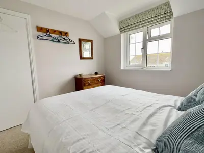 a bedroom with a white bed and a window at Choughs in Saint Minver