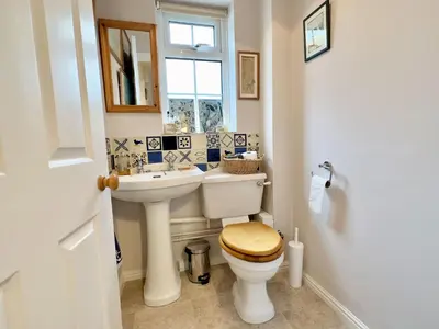 a bathroom with a toilet and a sink and a window at Choughs in Saint Minver