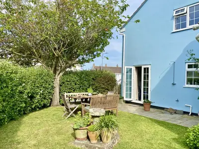 a blue house with a table and a tree in the yard at Choughs in Saint Minver