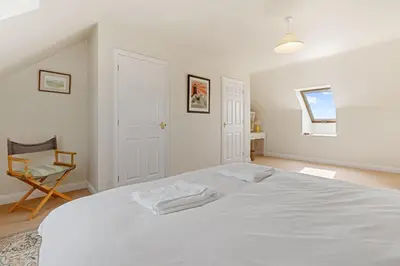 a bedroom with a white bed and a chair at Chough at Highcliffe in Polzeath