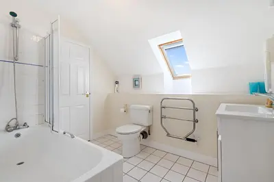 a white bathroom with a toilet and a sink at Chough at Highcliffe in Polzeath