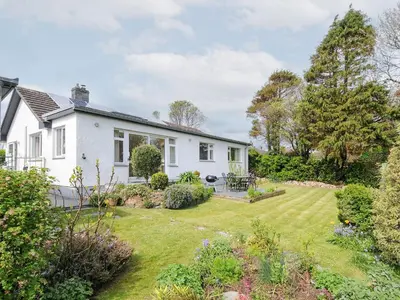 a white house with a garden in front of it at Chimings in Wadebridge