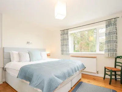 a white bedroom with a bed and a window at Chimings in Wadebridge