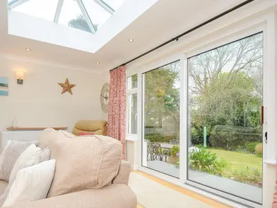 a conservatory with a couch and a large window at Chimings in Wadebridge