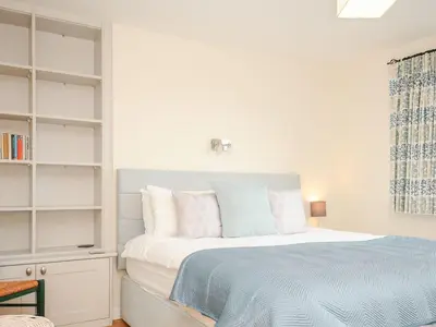 a white bedroom with a bed with blue and white pillows at Chimings in Wadebridge