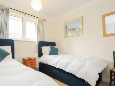 a bedroom with two beds and two windows at Chimings in Wadebridge