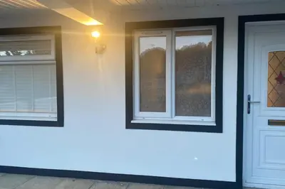 a white house with two windows and a door at Spacious 1-Bed Apartment - Sleeps 2 & Parking in Truro
