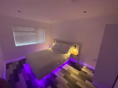 a bedroom with a bed with purple lights on it at Spacious 1-Bed Apartment - Sleeps 2 & Parking in Truro