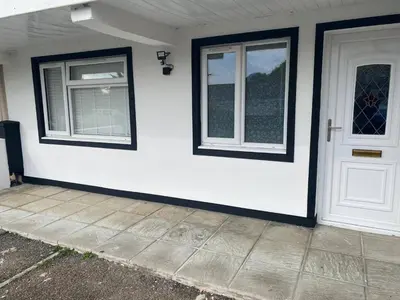a white house with two windows and a door at Spacious 1-Bed Apartment - Sleeps 2 & Parking in Truro