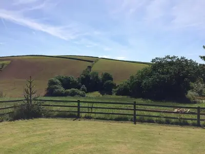 a field with a fence in front of a hill at Trecorme Barton in Quethiock