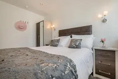 a white bedroom with a large bed and a nightstand at 1 Bed in Newquay oc-s32400 in Holywell Bay