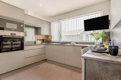 a kitchen with white cabinets and a large window at 1 Bed in Newquay oc-s32400 in Holywell Bay