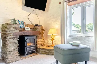 a living room with a stone fireplace and a chair at 2 Bed in Fowey oc-d32427 in Fowey