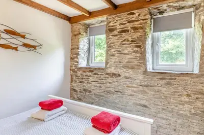 a bedroom with a stone wall and two windows at 2 Bed in Fowey oc-d32427 in Fowey