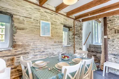 a dining room with a table and chairs and a stone wall at 2 Bed in Fowey oc-d32427 in Fowey