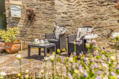 two chairs and a table in front of a stone wall at 2 Bed in Fowey oc-d32427 in Fowey