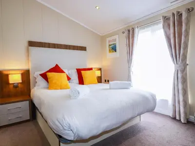 a bedroom with a large white bed with colorful pillows at The Maples 44 in St Austell