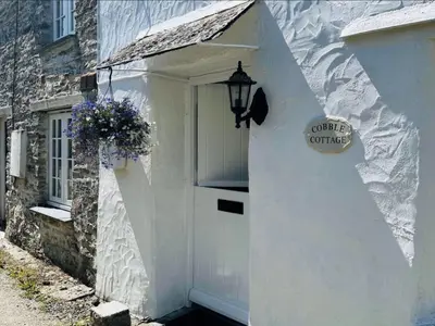 a white door with a sign on the side of a building at Holiday Home Riverside Cottage by Interhome in Lerryn