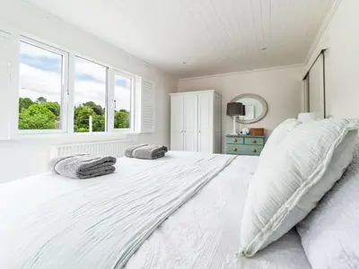 a white bedroom with a large white bed with two pillows at Holiday Home Riverside Cottage by Interhome in Lerryn