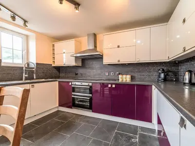 a kitchen with white cabinets and purple appliances at Holiday Home Tregony House by Interhome in Mevagissey