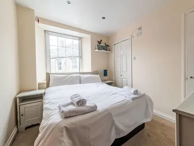 a bedroom with a large white bed with towels on it at Holiday Home Tregony House by Interhome in Mevagissey