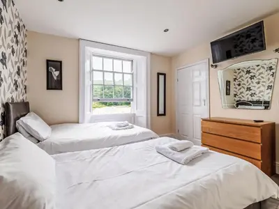 two beds in a bedroom with a mirror and a window at Holiday Home Tregony House by Interhome in Mevagissey