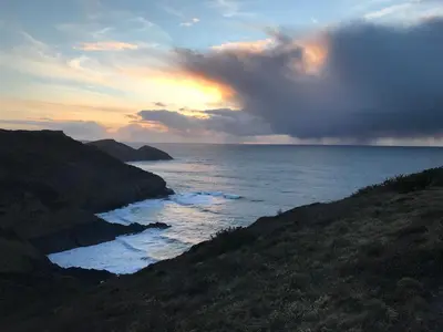 a sunset over the ocean with a cloudy sky at Cleave Cottage in Crackington Haven