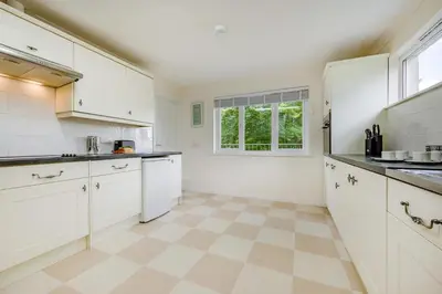 a large kitchen with white cabinets and a window at 2 Bed in Looe oc-g32529 in Looe