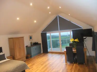 a bedroom with a bed and a large window with a table at The Count House in Saint Hilary
