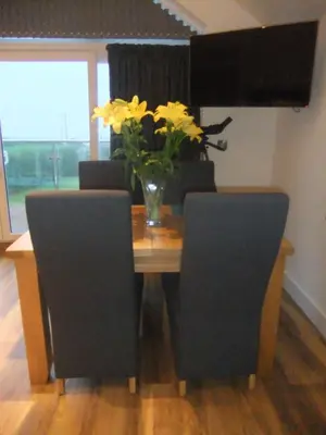 a table with chairs and a vase of flowers on it at The Count House in Saint Hilary