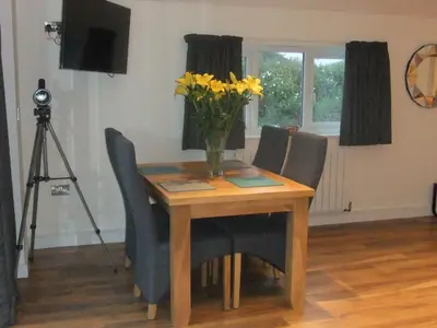 a wooden table with chairs and a vase of yellow flowers at The Count House in Saint Hilary