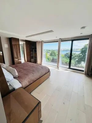 a bedroom with a large bed and large windows at Creek View House in Feock