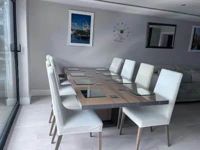 a dining room with a wooden table and white chairs at Creek View House in Feock