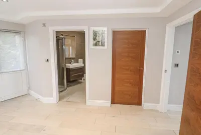 a hallway with a door and a bathroom with a sink at Creek View House in Feock
