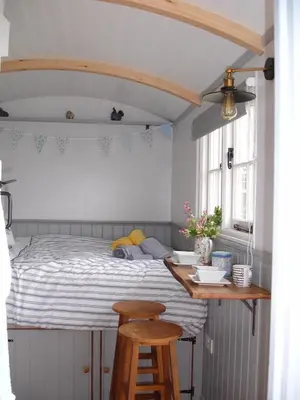 a bedroom with a bed with a table and two stools at Apple Tree Shepherd's Huts - Blackberry Hut in Saint Endellion