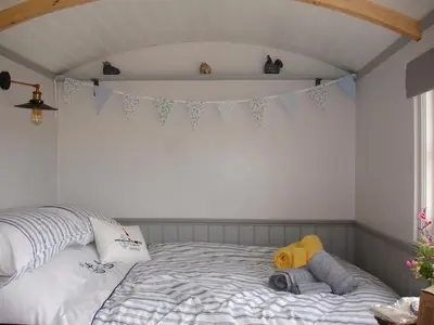a bedroom with a bed with a banner on the wall at Apple Tree Shepherd's Huts - Blackberry Hut in Saint Endellion