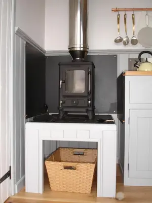 a kitchen with a white fireplace with a microwave at Apple Tree Shepherd's Huts - Blackberry Hut in Saint Endellion