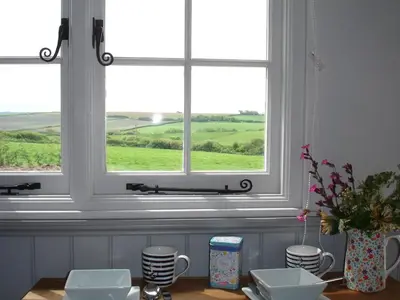 a room with two windows and a table with cups at Apple Tree Shepherd's Huts - Blackberry Hut in Saint Endellion