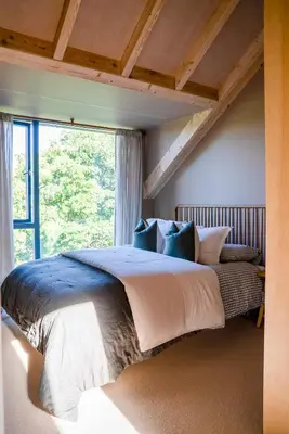 a bedroom with a large bed with a large window at The Architects Treehouse in Mount Hawke