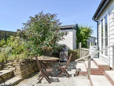 a picnic table and two chairs in front of a house at 1 Merope in Padstow