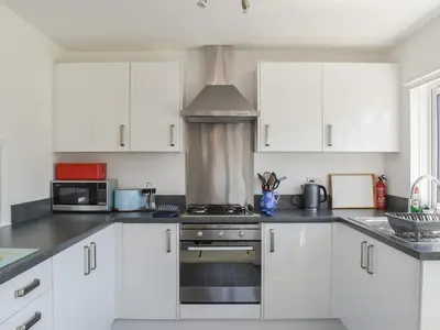 a kitchen with white cabinets and a stove top oven at 1 Merope in Padstow