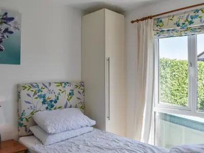a bedroom with a bed with a cabinet and a window at 1 Merope in Padstow