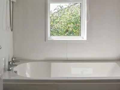 a white bathroom with a sink and a window at 1 Merope in Padstow