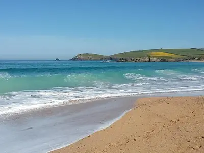 a sandy beach with the ocean and mountains in the background at 1 Merope in Padstow