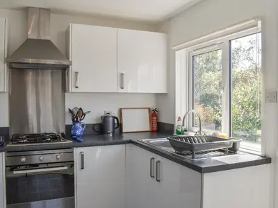 a kitchen with white cabinets and a sink and a window at 1 Merope in Padstow