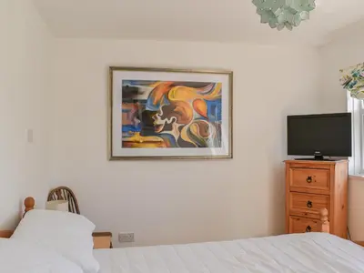 a bedroom with a bed and a painting on the wall at 1 Merope in Padstow