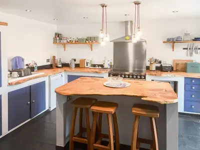 a kitchen with blue cabinets and a wooden counter top at The Saltings in Egloshayle