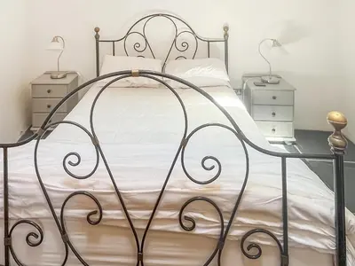 a bedroom with a metal bed with white sheets at The Saltings in Egloshayle