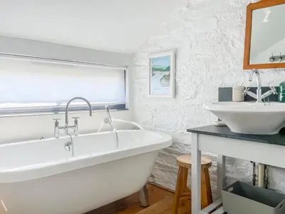 a white bathroom with a tub and a sink at The Saltings in Egloshayle