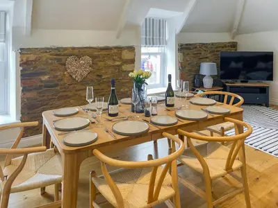 a dining room with a table with chairs and wine bottles at The Watch House in Saint Mawes